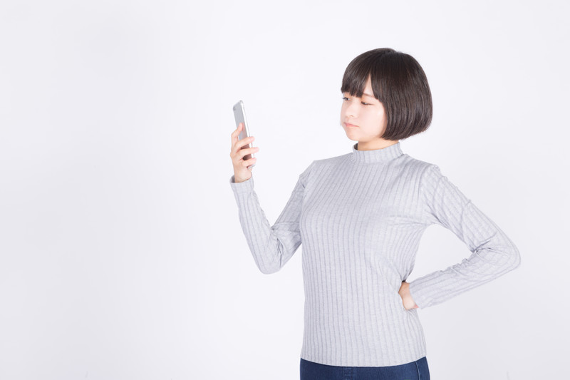 スマホを見て顔をしかめる女性